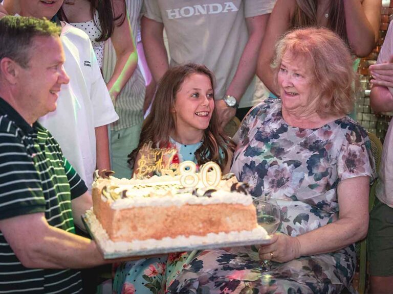 Family gathered around an 80th birthday cake at a party in Dublin