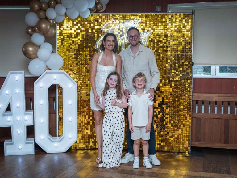 Family portrait in front of a balloon arch and gold backdrop at a 40th birthday in Dublin