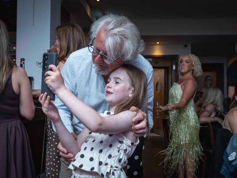 Grandfather hugging a young girl at a family birthday party in Dublin