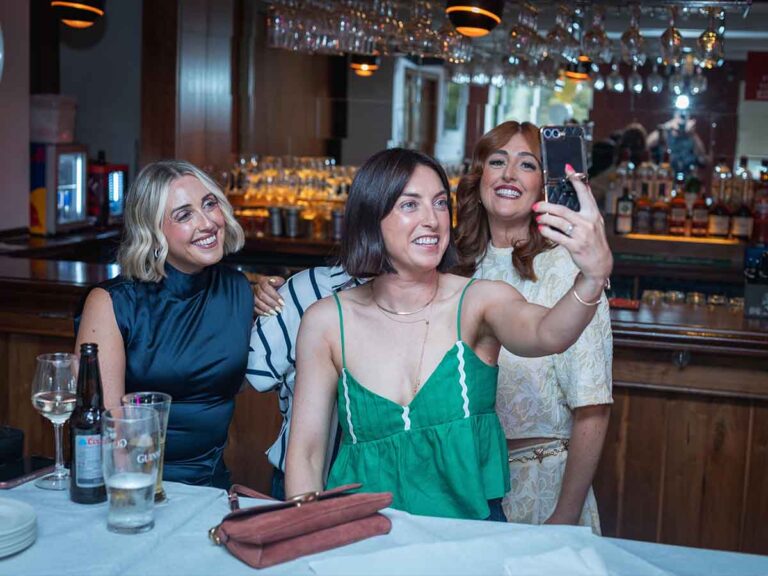 Friends taking a selfie at a birthday party table in a Dublin bar